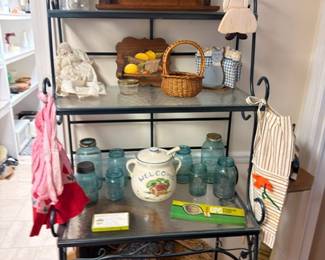 Black metal baker's rack with blue Mason jars, baskets, kitchen collectibles