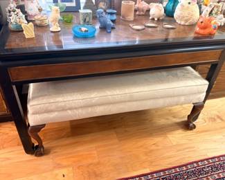 Dark wood console table with lower shelf, upholstered bench, assorted collectibles