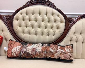 Victorian tufted ivory settee with carved dark wood frame, floral tapestry pillow