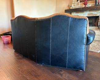 classic curved western-style leather sofa featuring a tufted seat back and saddle tan leather accents