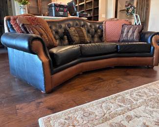 classic curved western-style leather sofa featuring a tufted seat back and saddle tan leather accents