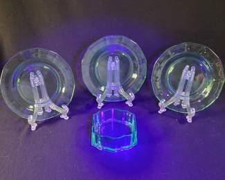 Lot # : 9 - Uranium Glass Plates and Dish Three uranium glass plates and one glass trinket keeper. Plates glow under UV light and display a green hue under normal light conditions. Condition appears good with no visible chips or cracks. Does not includes stands for the plates.