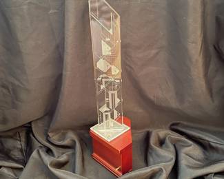 H95 - $100. "Harmonics Award" Column of Starphire Crystal designed by Susan Jacobs Lockhart in the spirit of Frank Lloyd Wright. Measures 15.5" tall. Etched on both sides showing various designs depending on viewpoint. Base has a hole and can be lighted. 