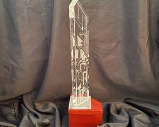H95 - $100. "Harmonics Award" Column of Starphire Crystal designed by Susan Jacobs Lockhart in the spirit of Frank Lloyd Wright. Measures 15.5" tall. Etched on both sides showing various designs depending on viewpoint. Base has a hole and can be lighted. 