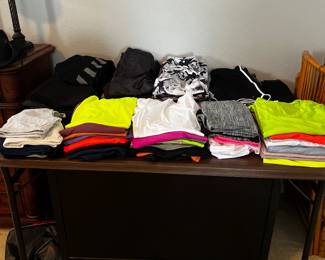 Table full of workout shirts and pants