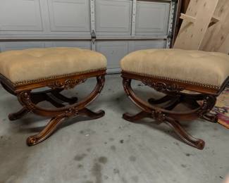 Tufted scroll-leg ottomans (pair). Ornate carved wood. Tan upholstery.