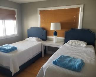 Twin beds with navy upholstered headboards; accent table