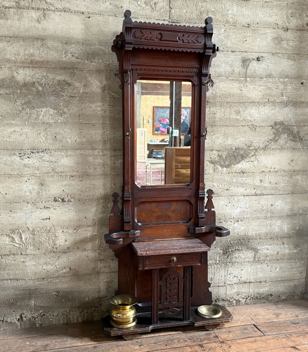 This lot features a stunning late 19th century Eastlake Victorian hall tree with a marble top drawer, umbrella trays, and brass hooks. This piece measures, 84” H x 35” W x 12” D.