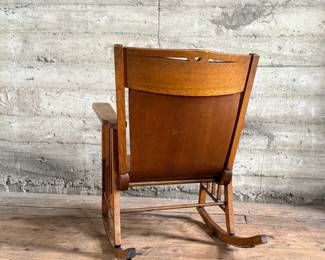 This lot features an antique Mission Arts and Crafts style rocking chair, with a curved back and in good sturdy condition. This chair measures, 33” H x 25” W x 30” D.