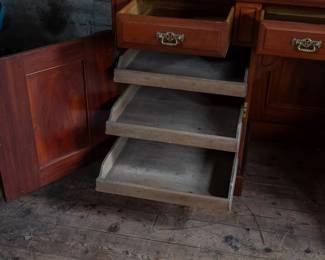 A large mahogany sideboard with an attached mirror by Aldis & Leggott, cabinet makers from Hull. The piece features four drawers, two side cabinets with pull-out shelves, and a specialized interior section for bottle storage. Decorative carvings on the legs and facade, as well as brass drawer pulls, highlight the craftsmanship. Dovetail joinery is observed on the drawers, indicating quality construction. The mirror shows minor silvering loss, and the wooden structure displays some signs of wear consistent with age, including small scratches and woodworm holes. Stamped “Aldis & Leggott, 17 Paragon Street, Hull”. This stunning sideboard measures 77” H X 78” W x 26” D.