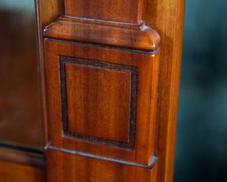 A large mahogany sideboard with an attached mirror by Aldis & Leggott, cabinet makers from Hull. The piece features four drawers, two side cabinets with pull-out shelves, and a specialized interior section for bottle storage. Decorative carvings on the legs and facade, as well as brass drawer pulls, highlight the craftsmanship. Dovetail joinery is observed on the drawers, indicating quality construction. The mirror shows minor silvering loss, and the wooden structure displays some signs of wear consistent with age, including small scratches and woodworm holes. Stamped “Aldis & Leggott, 17 Paragon Street, Hull”. This stunning sideboard measures 77” H X 78” W x 26” D.