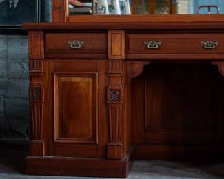 A large mahogany sideboard with an attached mirror by Aldis & Leggott, cabinet makers from Hull. The piece features four drawers, two side cabinets with pull-out shelves, and a specialized interior section for bottle storage. Decorative carvings on the legs and facade, as well as brass drawer pulls, highlight the craftsmanship. Dovetail joinery is observed on the drawers, indicating quality construction. The mirror shows minor silvering loss, and the wooden structure displays some signs of wear consistent with age, including small scratches and woodworm holes. Stamped “Aldis & Leggott, 17 Paragon Street, Hull”. This stunning sideboard measures 77” H X 78” W x 26” D.