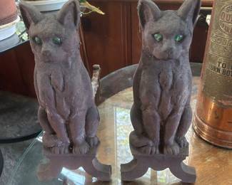 A pair of vintage cast iron cat andirons with green glass eyes