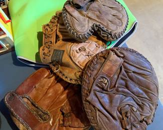 3 well worn catcher mitts and a fielder's mitt