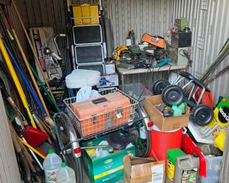 Instead of a garage, we have a tool shed, including an adult-sized tricycle with a basket, a three-step stepladder, a garden weeding seat, and gardening implements.