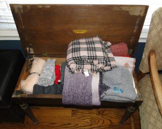 Piano bench filled with scarves, and other winter time accessories