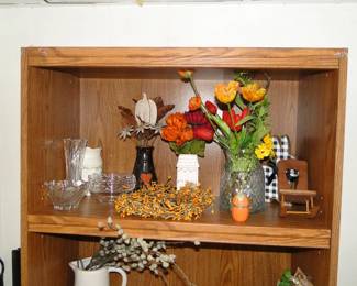 Very nice tall, wooden bookcase showcasing some faux floral items