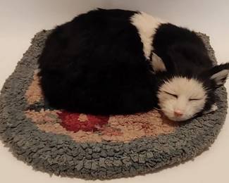Realistic looking faux sleeping cat and vintage hook rug