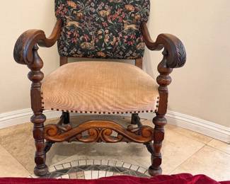 antique armchair featuring a hand-carved wood frame and a tapestry upholstery