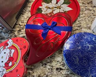 Assorted Decorative Tins Heartshaped Dove Chocolate Tin, Hello Kitty Tin, and Round Poinsettia Tin