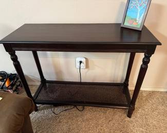 $68 - Black console with cane bottom shelve. 