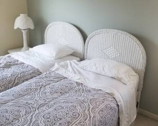 Twin beds with wite wicker headboards; wicker nightstand; wicker table lamp