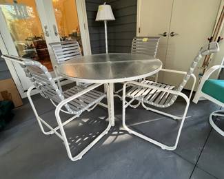 C28 - $350. Woodard Furniture Glass Top Table & 4 Vinyl Strap Chairs. Measures 47.5" round x 28" tall. Chairs are 23.5" x 25.5" x 36" tall. Has been used on a screened in porch - a few very minor rust spots
