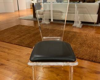 Modern clear acrylic dining chair with black seat cushion, minimalist contemporary design.