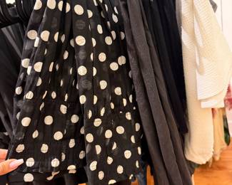 Black and white polka dot sleeveless blouse with gathered waist detail.