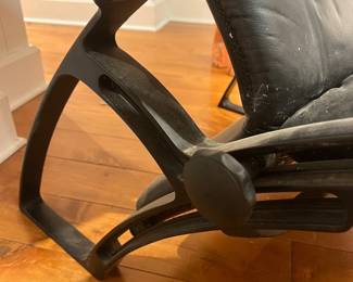 Black Leather Chaise Lounge – Modern black leather reclining chaise lounge chair with curved metal frame and head cushion, minimalist contemporary design.