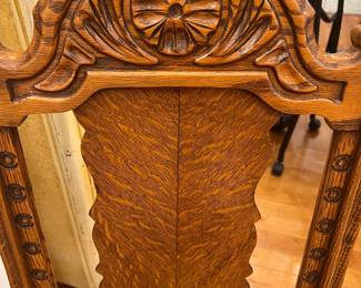 Antique carved oak dining chair with ornate crest and floral tapestry seat.