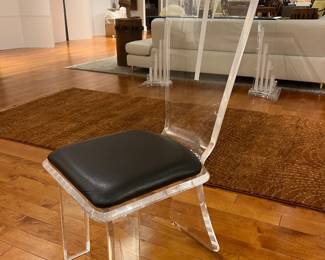 Modern clear acrylic dining chair with black seat cushion, minimalist contemporary design.