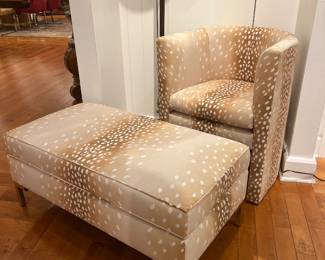 Modern barrel accent chair with matching ottoman in beige spotted upholstery and brass legs.