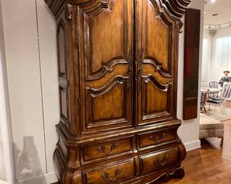 Ornate French Provincial style wooden armoire with carved details and multiple drawers.
