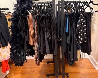 Designer Women’s Fashion Boutique Interior Display – Clothing and Shoe Retail Shop Setup.Rolling garment rack with black clothing assortment including dresses, skirts, and feather boa accessory.