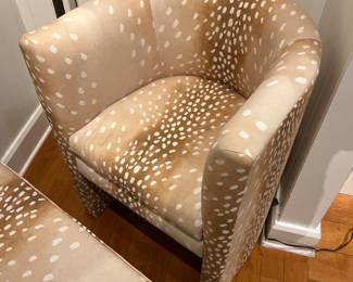 Modern upholstered barrel chair in tan spotted fabric with curved arms.