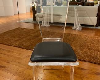 Modern clear acrylic dining chair with black seat cushion, minimalist contemporary design.