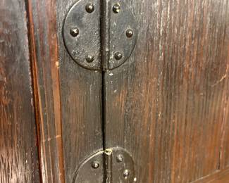 Asian style dark wood cabinet with paneled doors and decorative iron hardware.