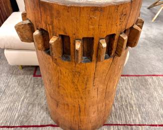 A large cylindrical wooden block with carved wedge-shaped slots around its middle.