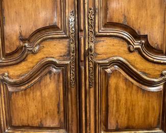 Ornate French Provincial style wooden armoire with carved details and multiple drawers.