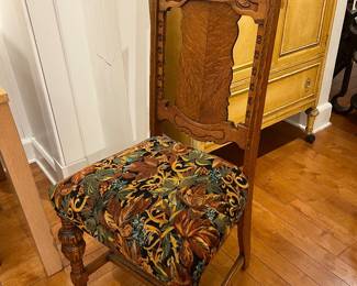 Antique carved oak dining chair with ornate crest and floral tapestry seat.