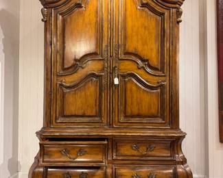 French Provincial armoire features a dramatic triple-arched bonnet top and a hand-carved bombé-style base with four drawers, serving as an exceptional example of 19th-century Louis XV revival craftsmanship.