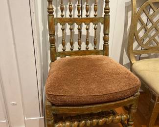 Vintage spindle-back wooden chair with turned legs and textured seat cushion.