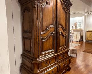 Ornate French Provincial style wooden armoire with carved details and multiple drawers.