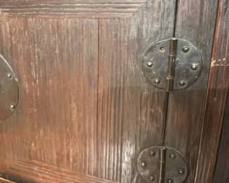 Asian style dark wood cabinet with paneled doors and decorative iron hardware.