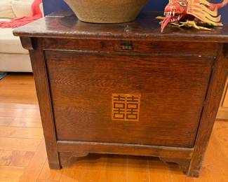 Dark wood storage chest or trunk with Asian-style double happiness motif, topped with decorative bowl and carved dragon figure.