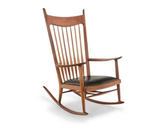258 Sam Maloof (1916-2009) A walnut rocking chair commissioned for John Kenneth Hull (1901-1985, CA), mid/late 20th century Bottom seat rail burn marked with Sam Maloof brand; and impressed: J. K. Hull With spindle back and black leather upholstered seat cushion 45.5" H x 28" W x 41" D Estimate: $10,000 - $15,000
