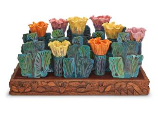 84 Eddie Dominguez (b. 1957) "Mixed Zinnias" Glazed ceramic cups, plates, and bowls set in a carved wood base Most cups and bowls marked for assembly Comprising 7 leaf-form plates, 8 floriform bowls, 16 cups, and 1 slotted wood base with leather top 32 pieces Arranged: 20.5" H x 37" W x 19" D; Base: 4.25" H x 37" W x 14.5" D Estimate: $1,200 - $1,800