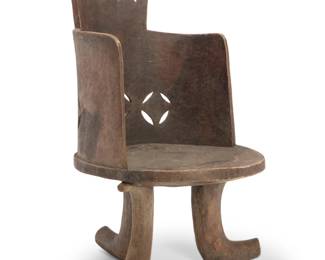 433 An African carved wood chair 20th century The barrel-form chair with pierced details to seatback, raised on three curved legs 45" H x 29" W x 30" D Estimate: $400 - $600