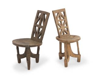 434 Two African carved wood chairs 20th century Each with openwork back over a circular seat raised on a stylized tripod base 2 pieces Taller: 33.75" H x 15.25" W x 16.25" D; Shorter: 32.75" H x 15.75" W x 21.5" D Estimate: $300 - $500
